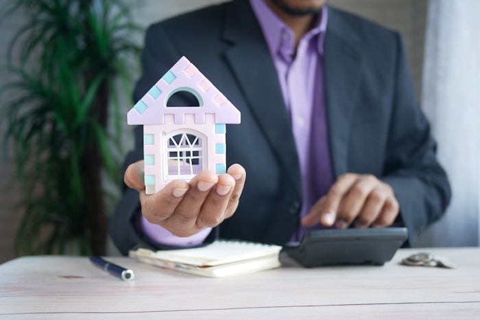 Man holding the shape of a house in his hand.